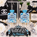 Chanel No. 5 L'Eau Blue Glitter Perfume Bottle Dangle Earrings on display stand with Chanel branded backdrop