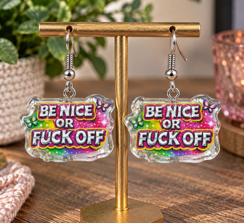 Be Nice or F*ck Off dangle earrings on gold display stand – lifestyle shot