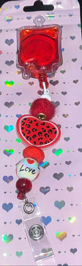 Handmade red blood bag badge reel displayed on heart-patterned backing card