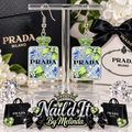 Prada Milano Green Glitter Perfume Bottle Dangle Earrings on display stand with Prada branded backdrop