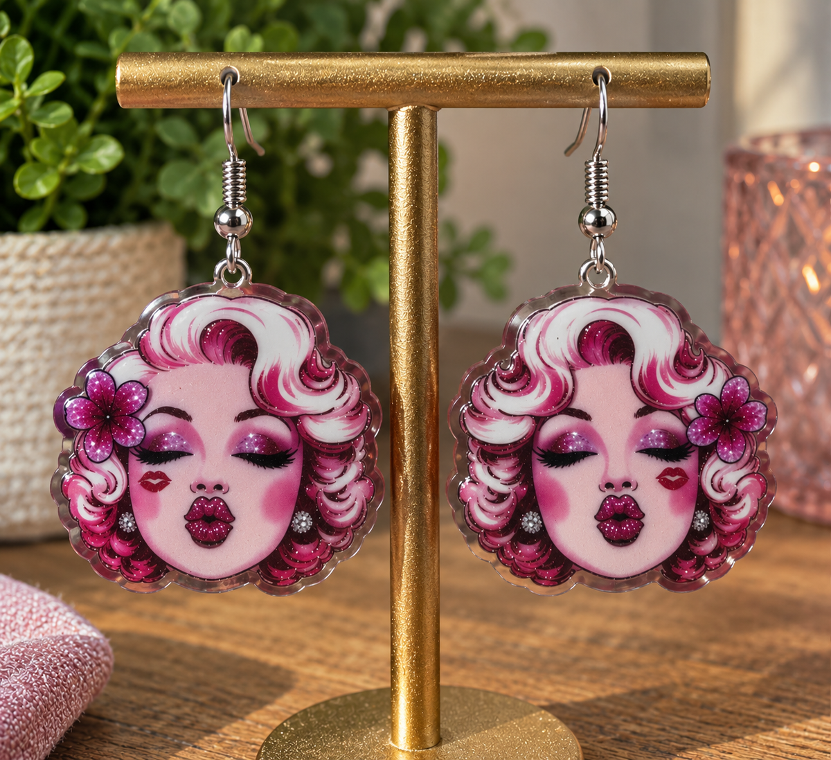 Pink glam icon kisses dangle earrings on gold display stand – pink lifestyle flat lay