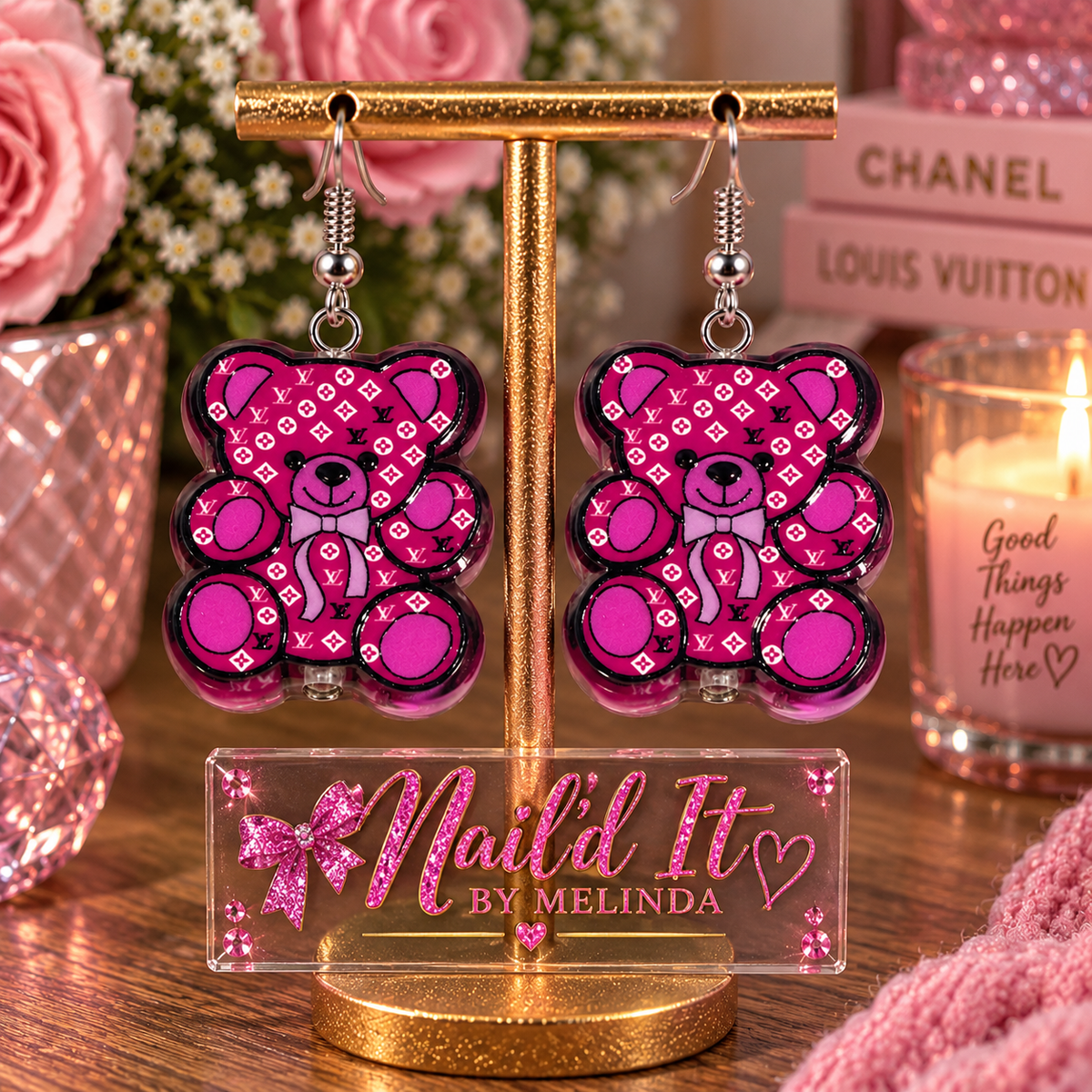 Pink teddy bear designer-inspired dangle earrings on gold display stand – Nail'd It By Melinda branded lifestyle shot