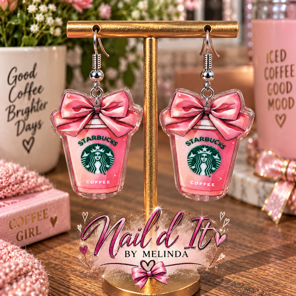 Starbucks pink cup dangle earrings on gold display stand – lifestyle shot with coffee backdrop