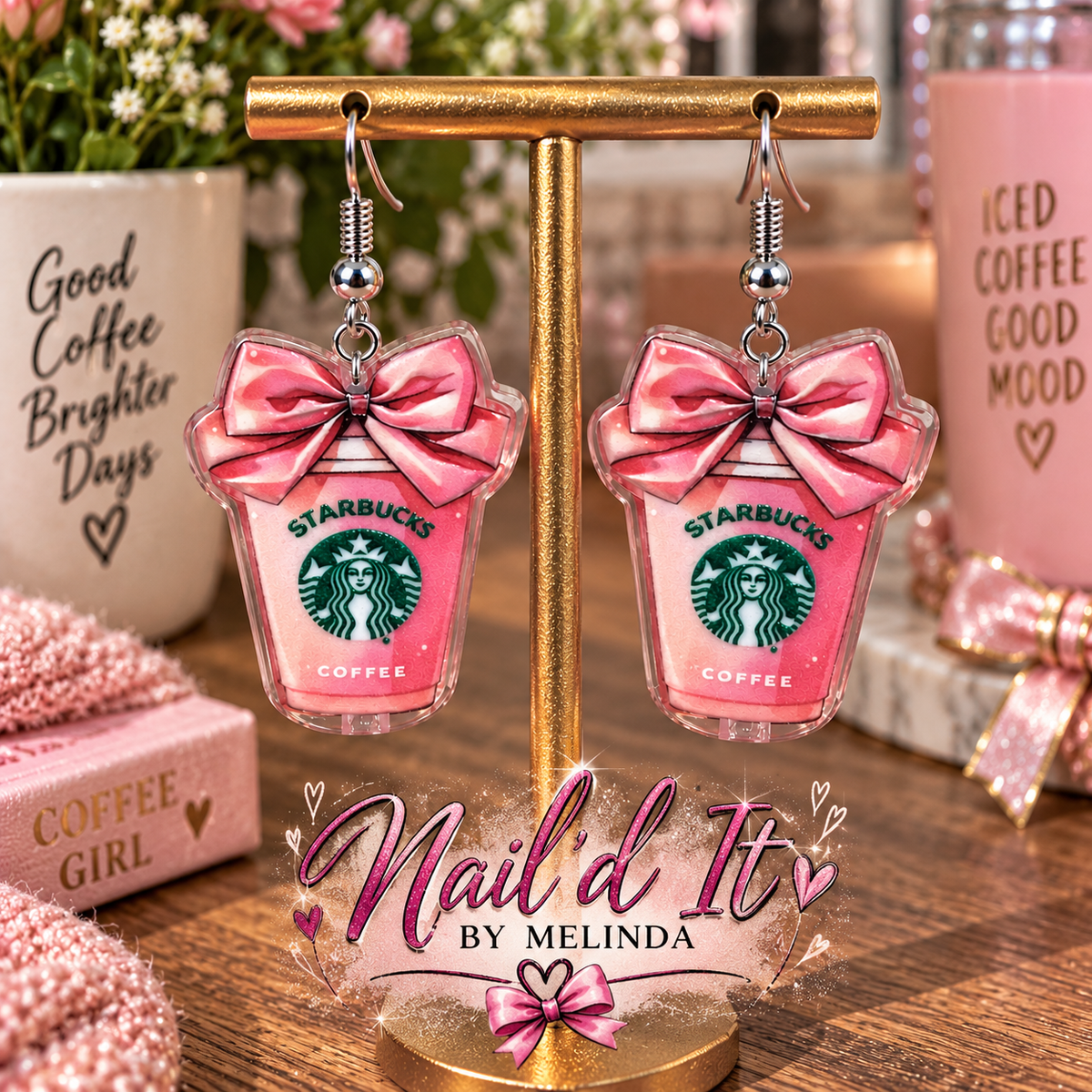 Starbucks pink cup dangle earrings on gold display stand – lifestyle shot with coffee backdrop